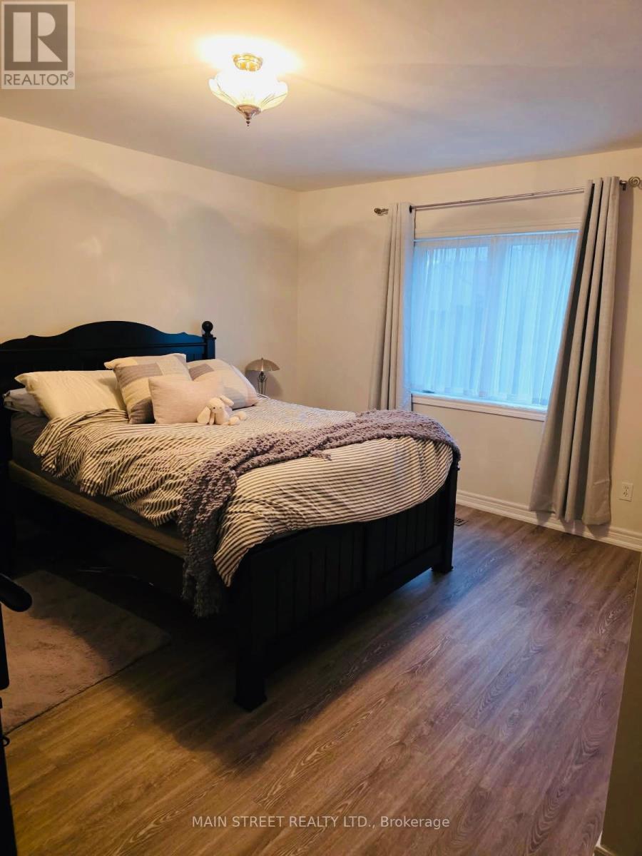 A bedroom with a bed, wooden floor, and a window with curtains.