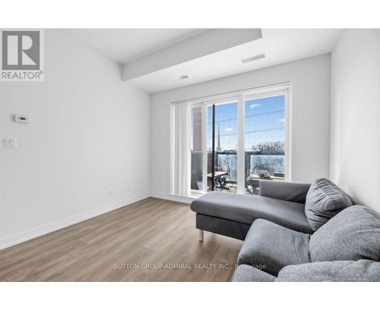 A living room with a grey couch and a large window.