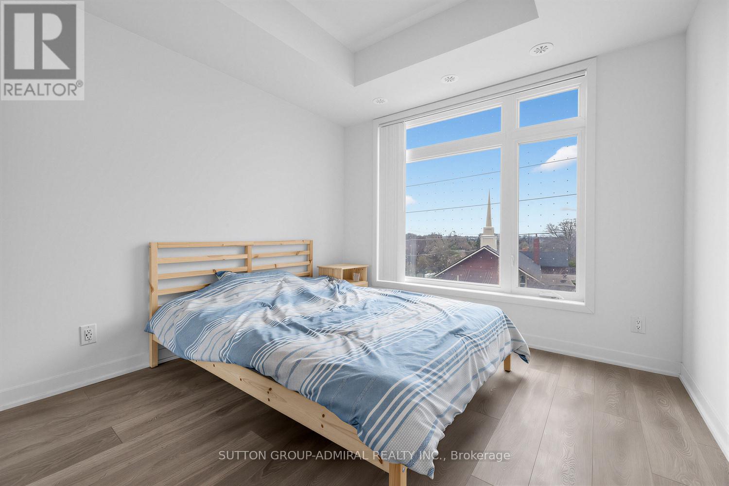 A bedroom with a bed and a window overlooking a church.