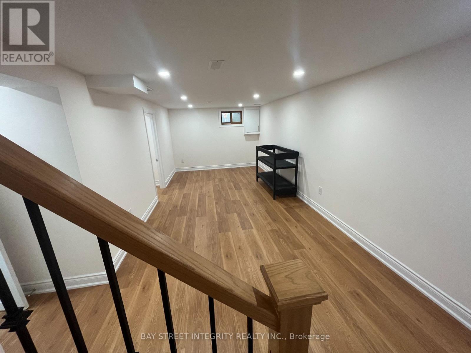 A spacious room with wooden floors and a staircase leading to another level.