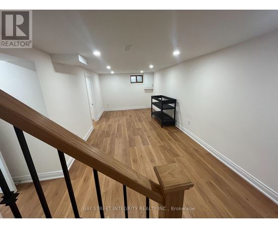A spacious room with wooden floors and a staircase leading to another level.