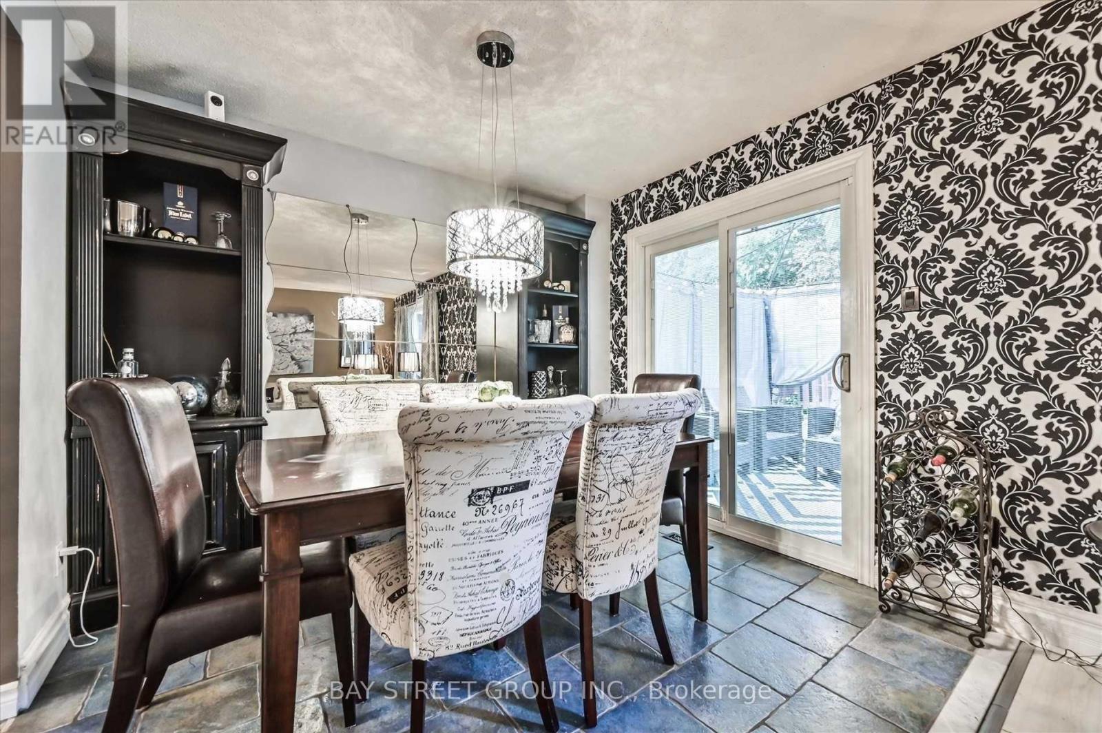 A dining room with a table set for two and a chandelier hanging from the ceiling.