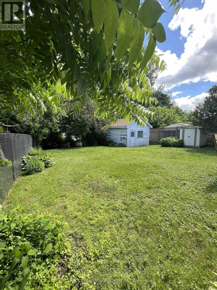 A backyard with a fence, a shed, and a house.