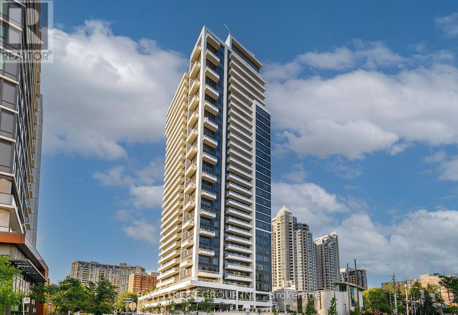 A tall, modern building with many windows stands in the foreground of a cityscape.