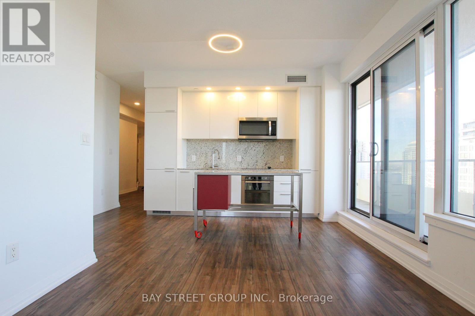 A modern kitchen with white cabinets and a red island.