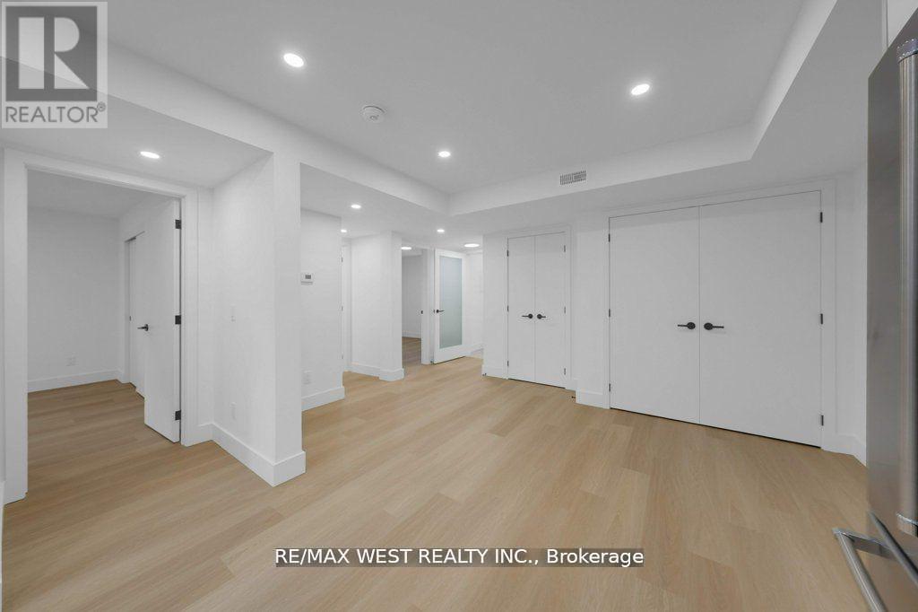A spacious room with wooden flooring and white walls, with a logo of RE/MAX West Realty Inc. in the bottom left corner.