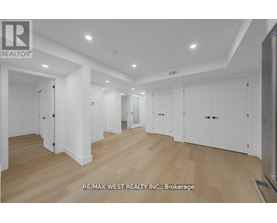 A spacious room with wooden flooring and white walls, with a logo of RE/MAX West Realty Inc. in the bottom left corner.