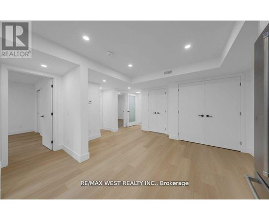 A spacious room with wooden flooring and white walls, with a logo of RE/MAX West Realty Inc. in the bottom left corner.
