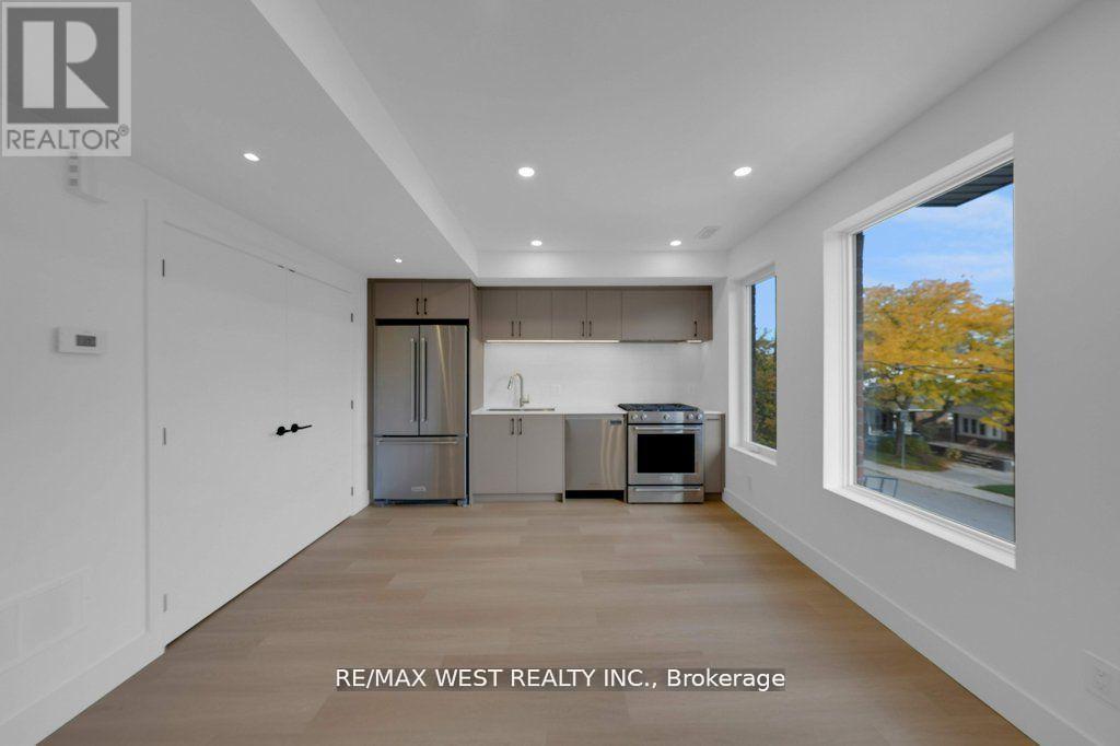 A spacious kitchen with white cabinets and a large window.