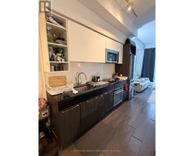A kitchen with dark wood floors and white cabinets.