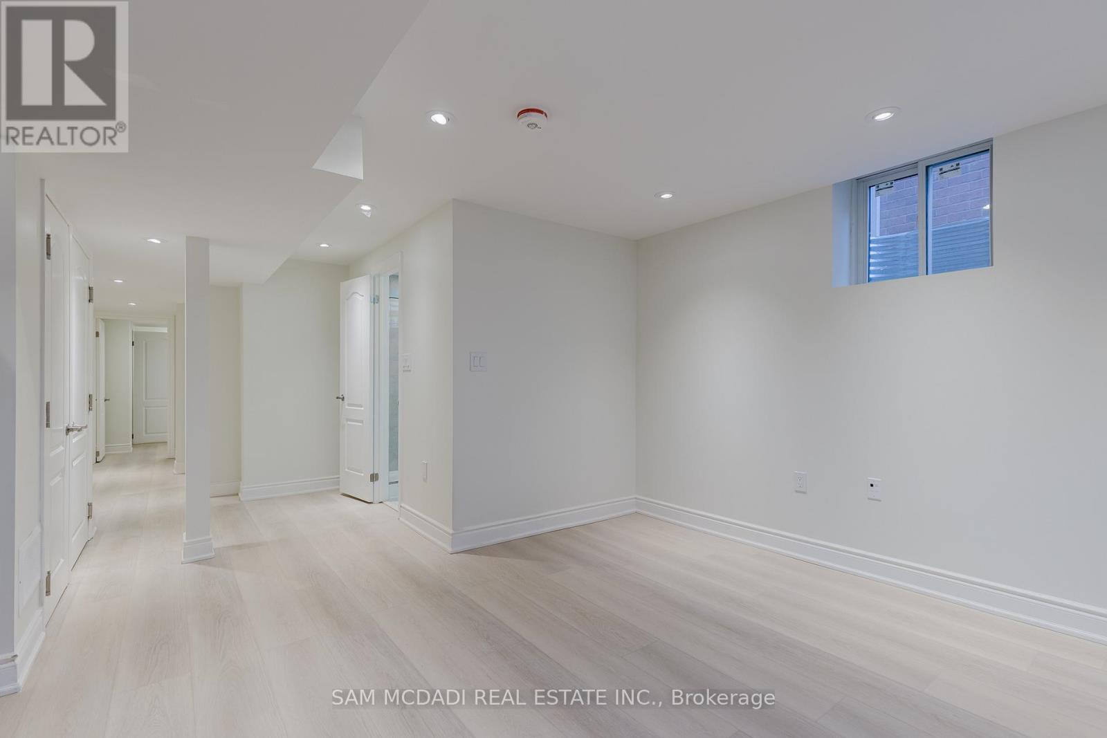 A spacious room with white walls and wooden flooring.