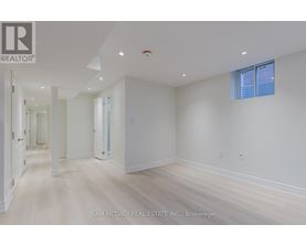 A spacious room with white walls and wooden flooring.