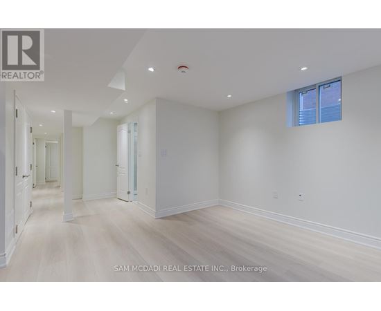 A spacious room with white walls and wooden flooring.