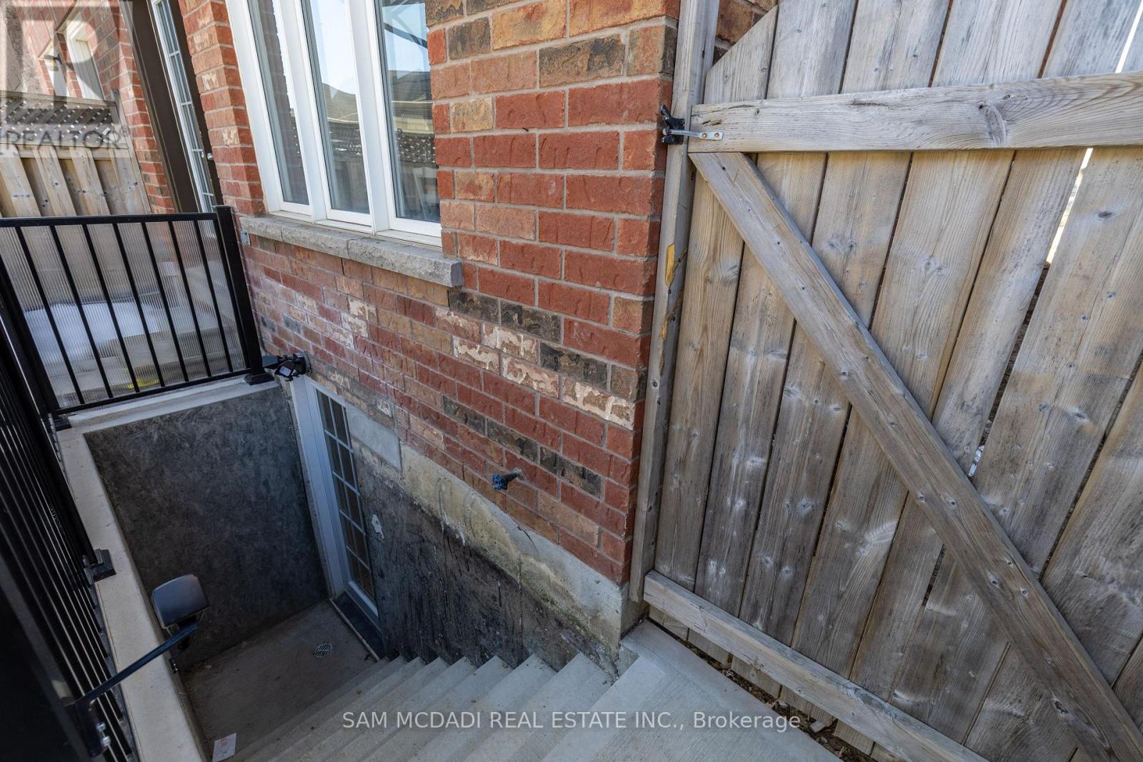 A wooden gate is closed to a brick wall.