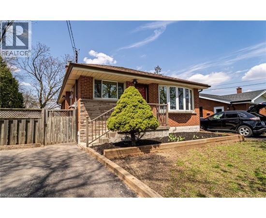 A house with a small tree in front and a car parked in the driveway.