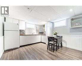A kitchen with white appliances and a wooden floor.