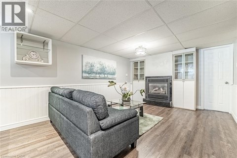 A grey couch in a living room with a fireplace and a painting on the wall.