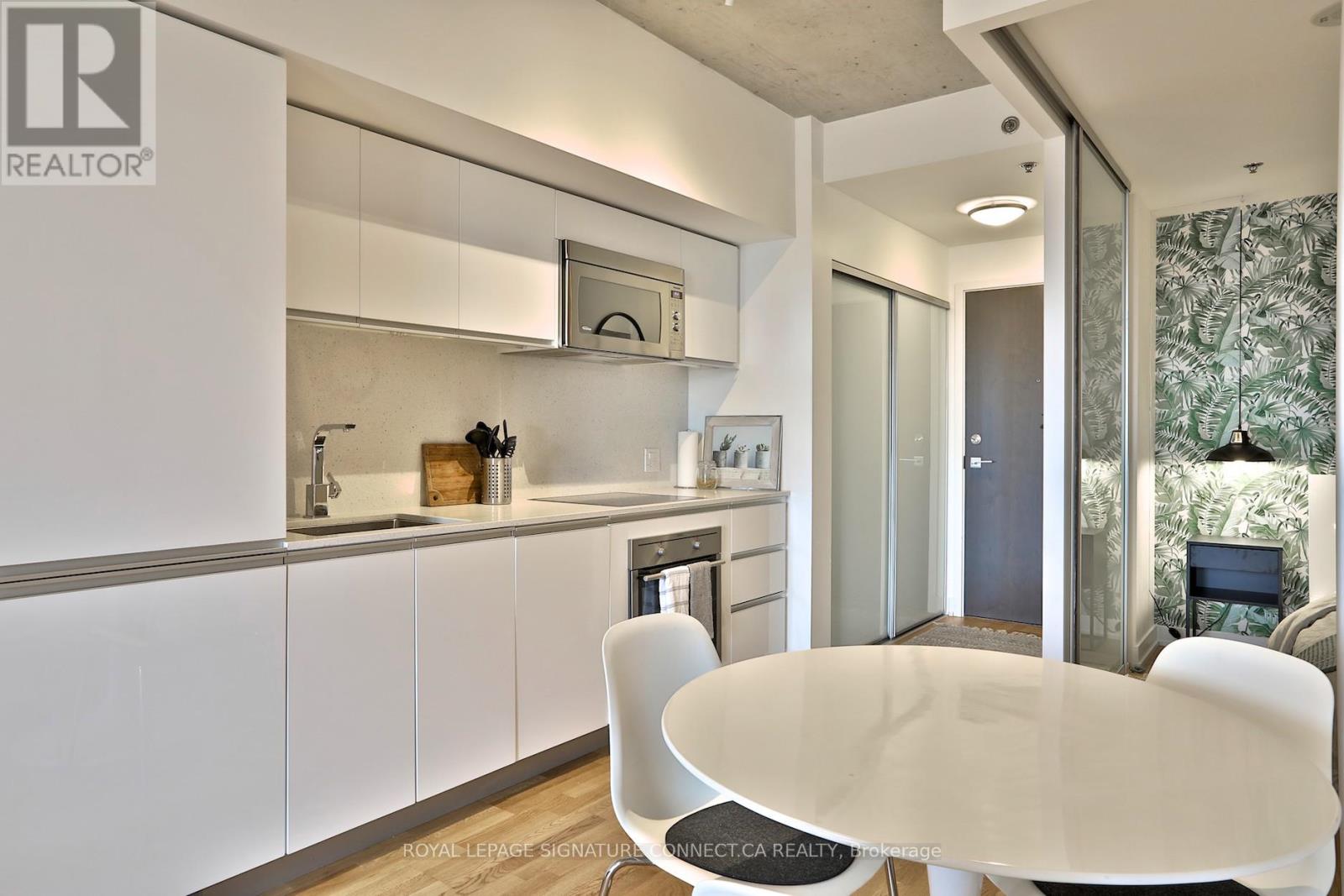 A modern kitchen with white cabinets and a dining table.