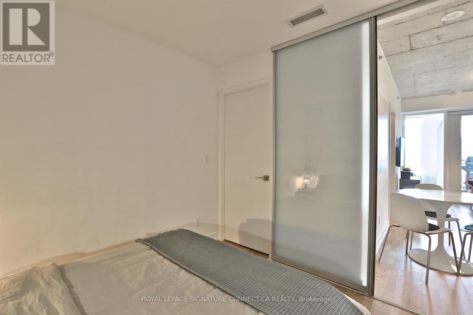 A bedroom with a bed covered in white sheets and a glass door leading to a balcony.