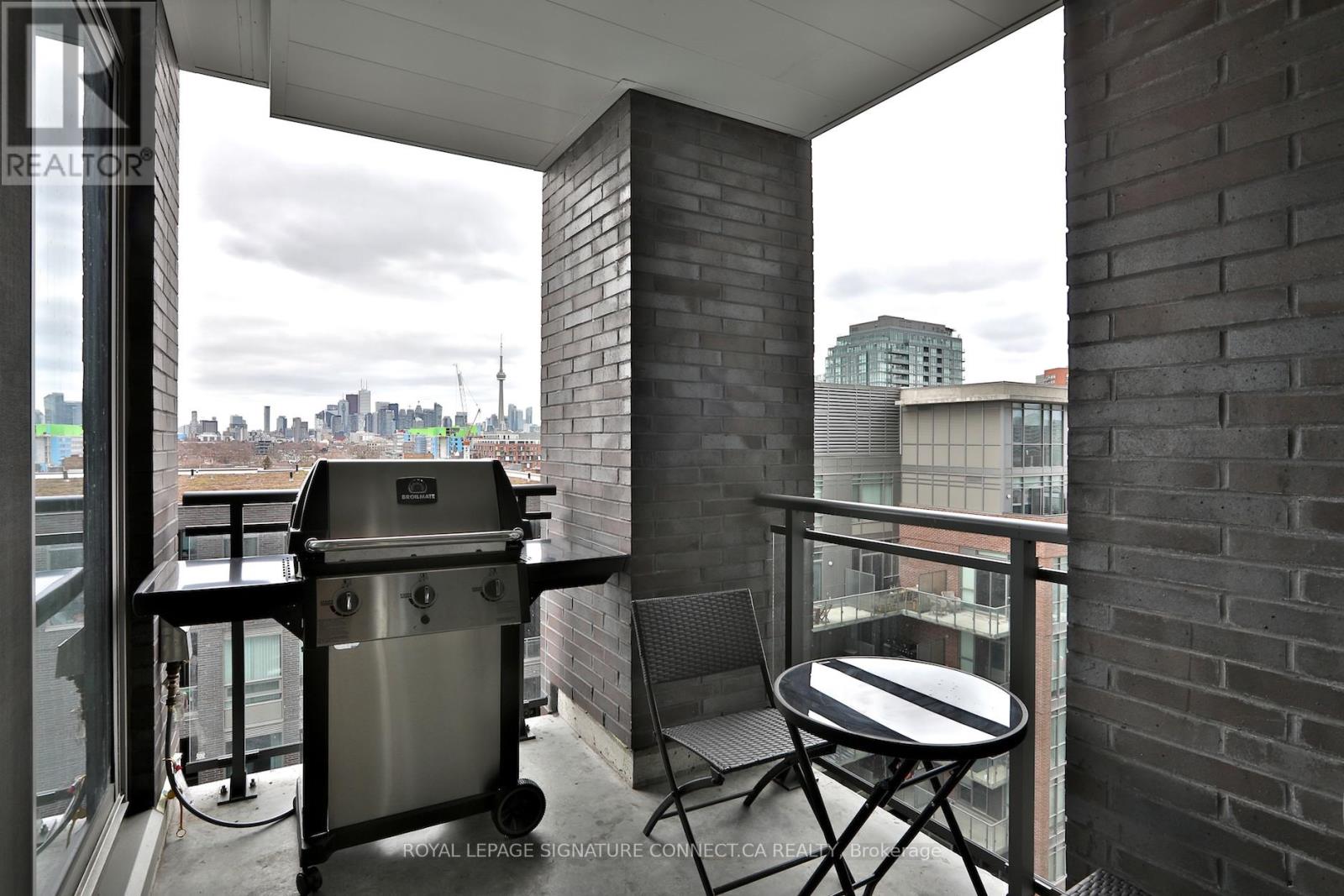 A balcony with a table and chairs and a BBQ grill.