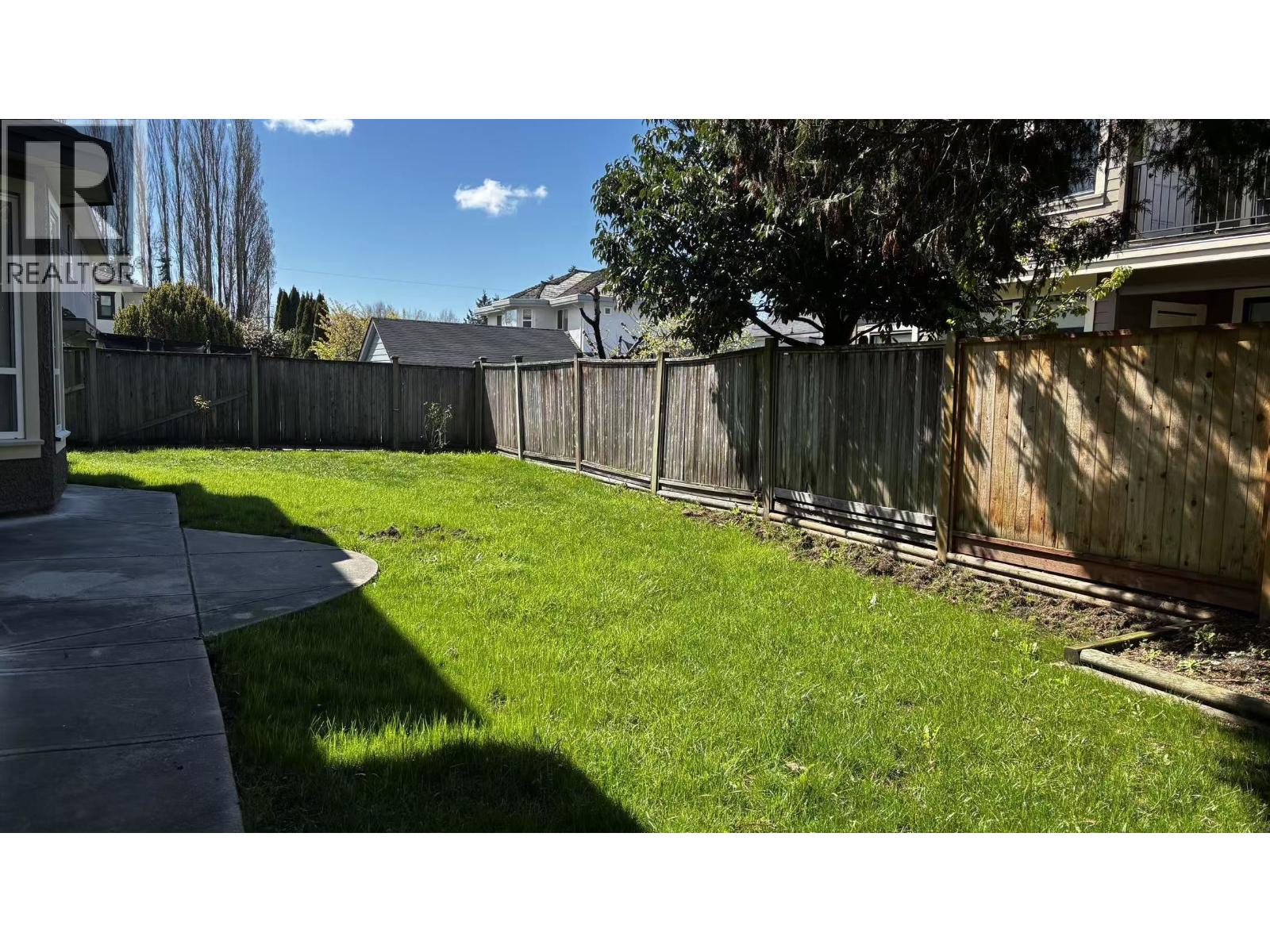 A backyard with a wooden fence and a green lawn.