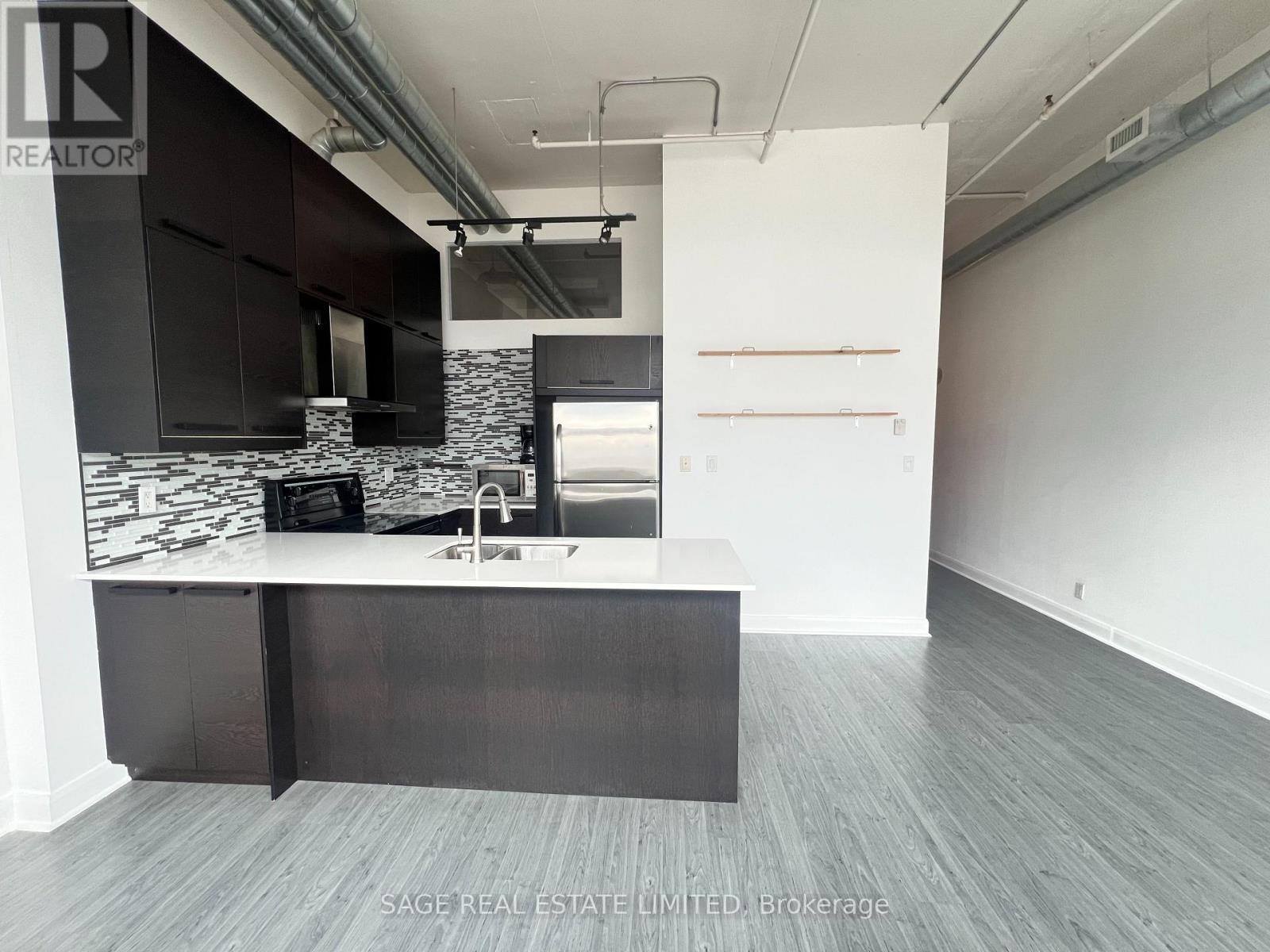 A modern kitchen with a black and white marble backsplash and dark wood flooring.