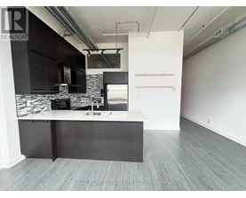 A modern kitchen with a black and white marble backsplash and dark wood flooring.