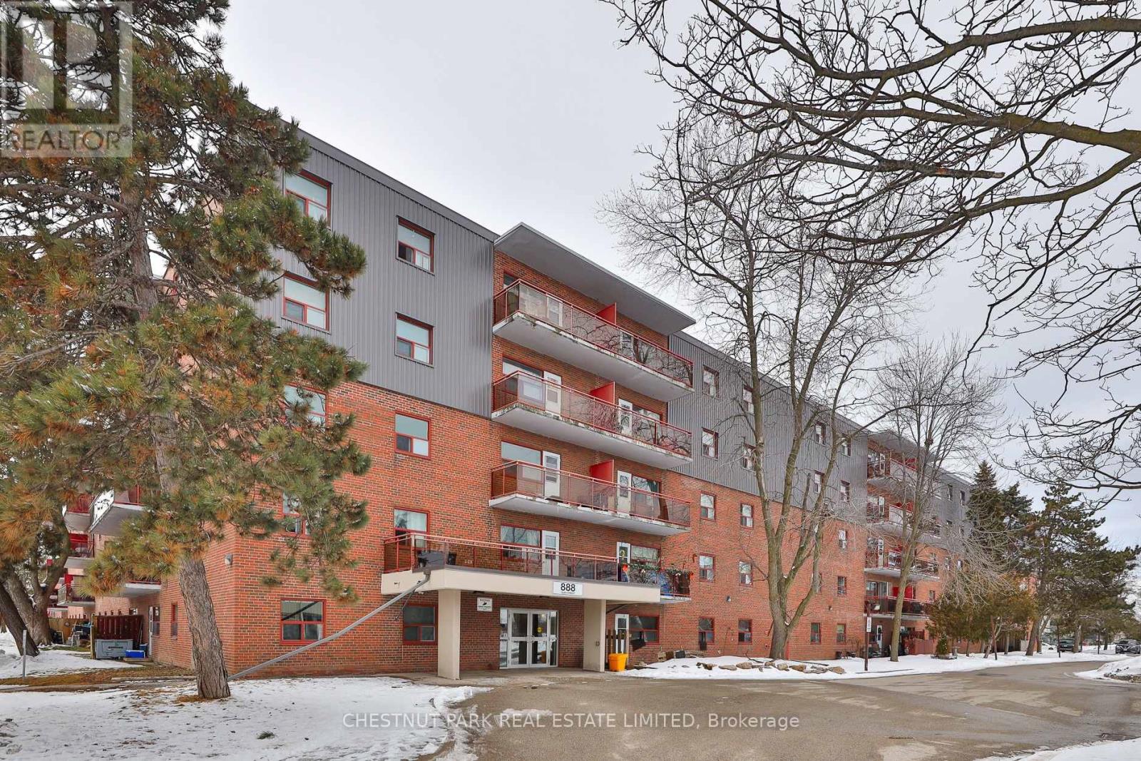 A large apartment building with a red brick facade and multiple balconies.