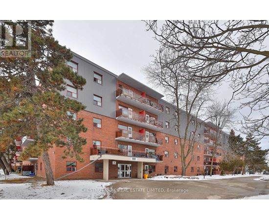 A large apartment building with a red brick facade and multiple balconies.