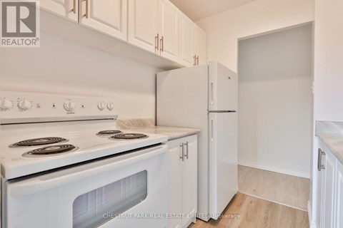A white stove and refrigerator in a kitchen with white cabinets.
