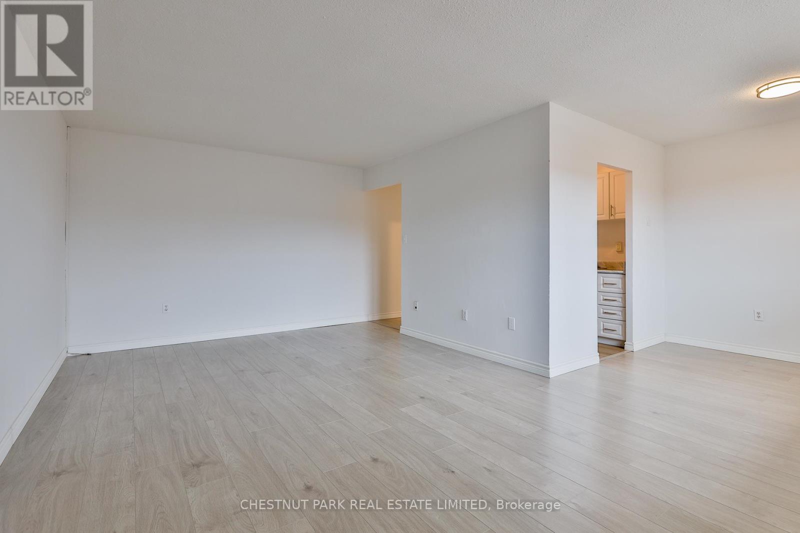 A large empty room with wood flooring and white walls.