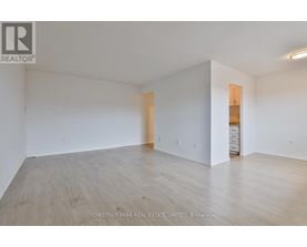 A large empty room with wood flooring and white walls.