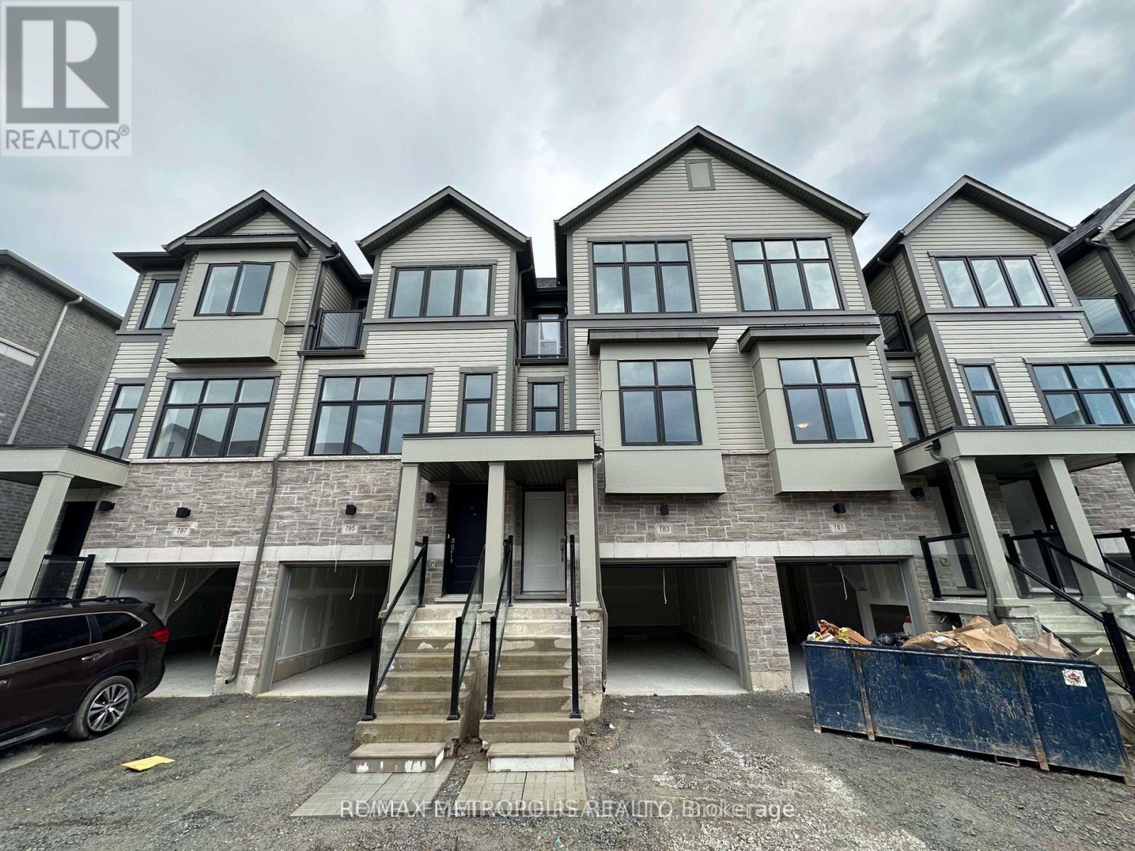A row of new houses with a car parked in front of the first one.