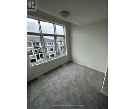 A room with a large window overlooking a street with buildings.