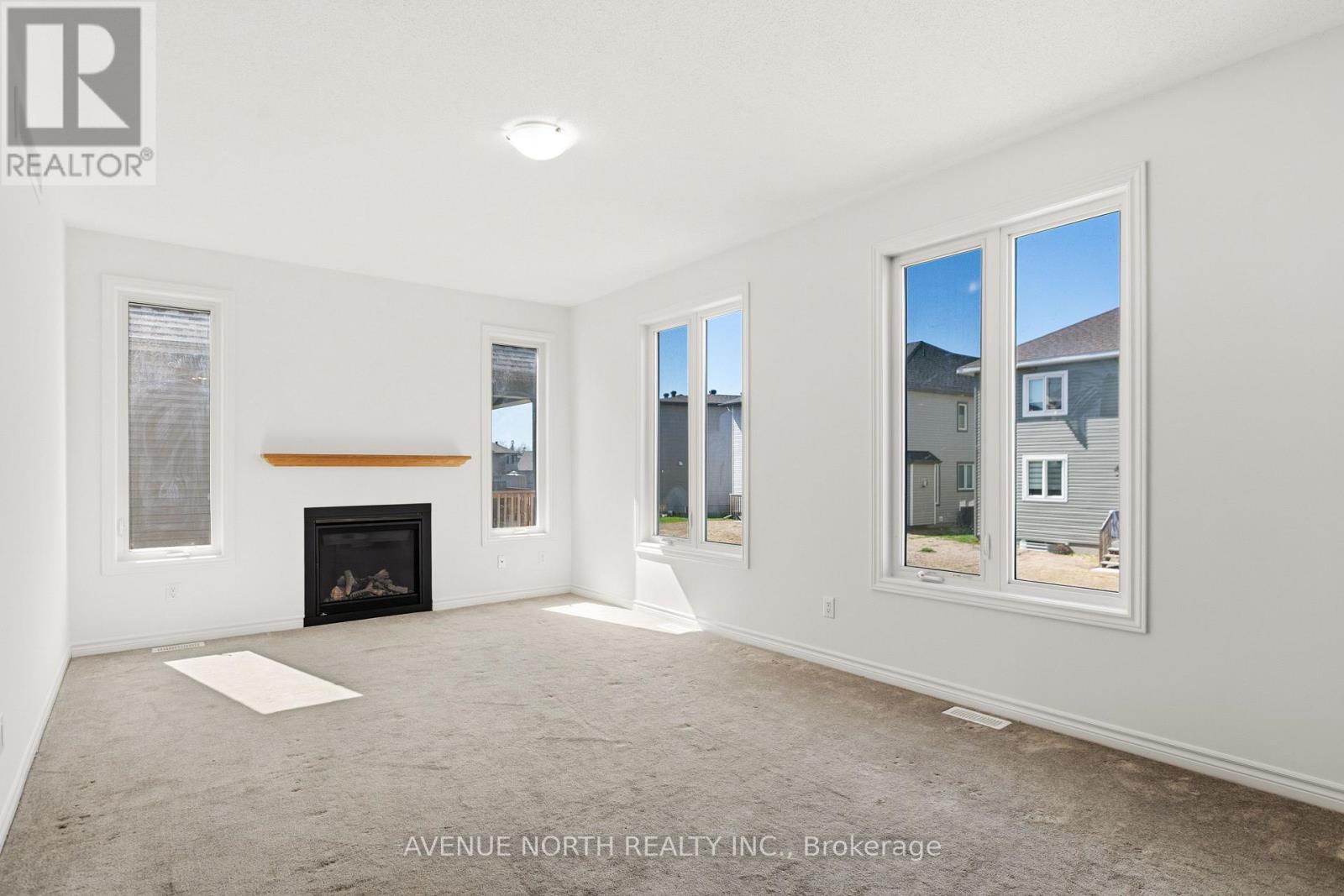 A spacious living room with a fireplace and large windows.