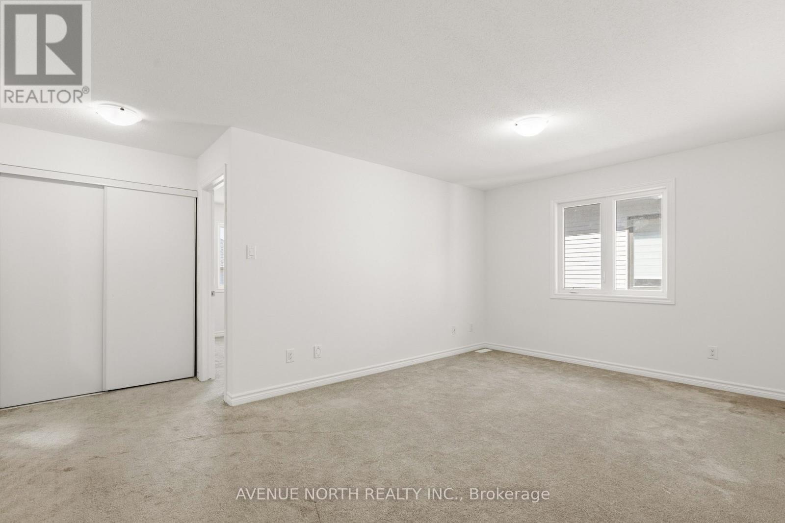 A white bedroom with a window and a door.