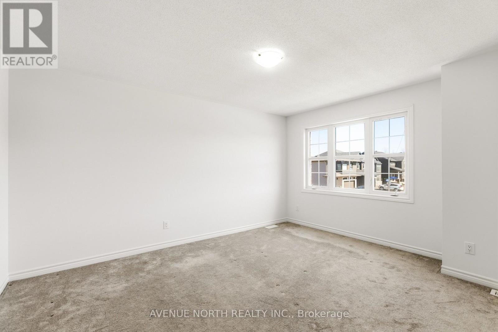 A large empty room with a window showing a view of other buildings.