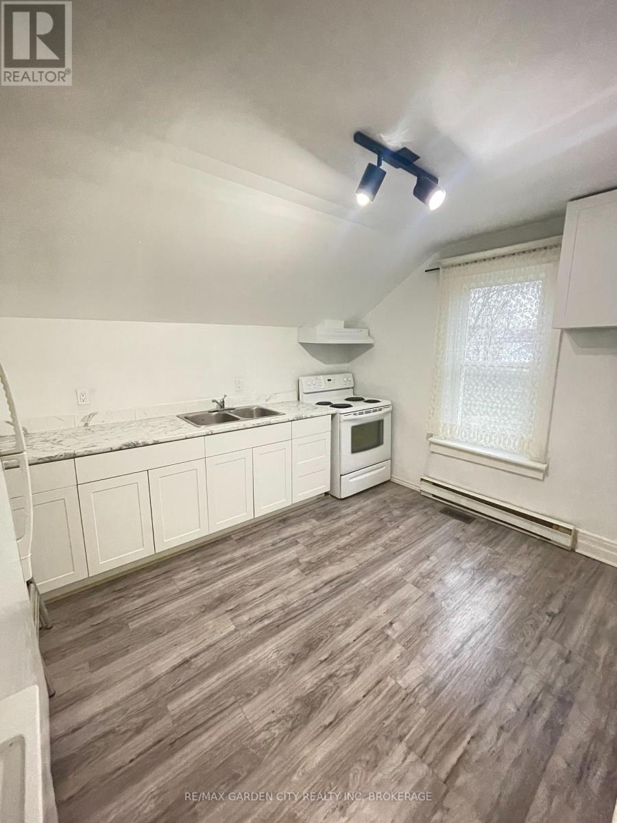 A kitchen with white cabinets and a wooden floor.