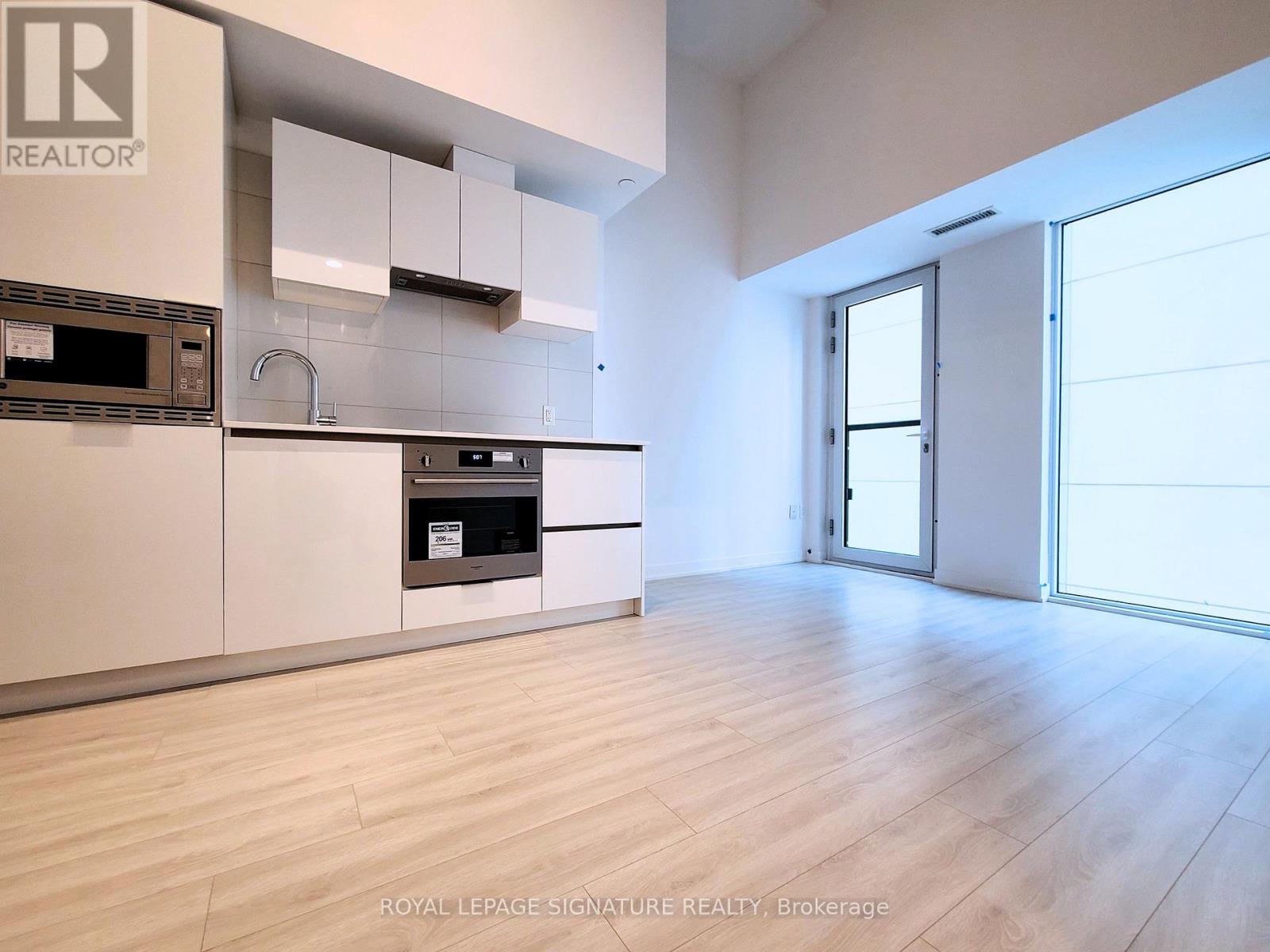 A modern kitchen with white cabinets and a wooden floor.