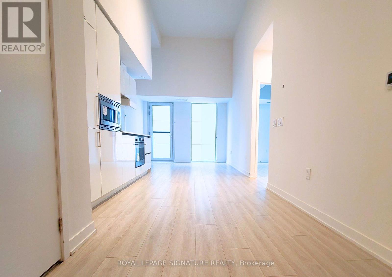 A spacious room with wooden flooring and white walls.