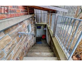 A staircase with a metal railing leads down to a small basement area.