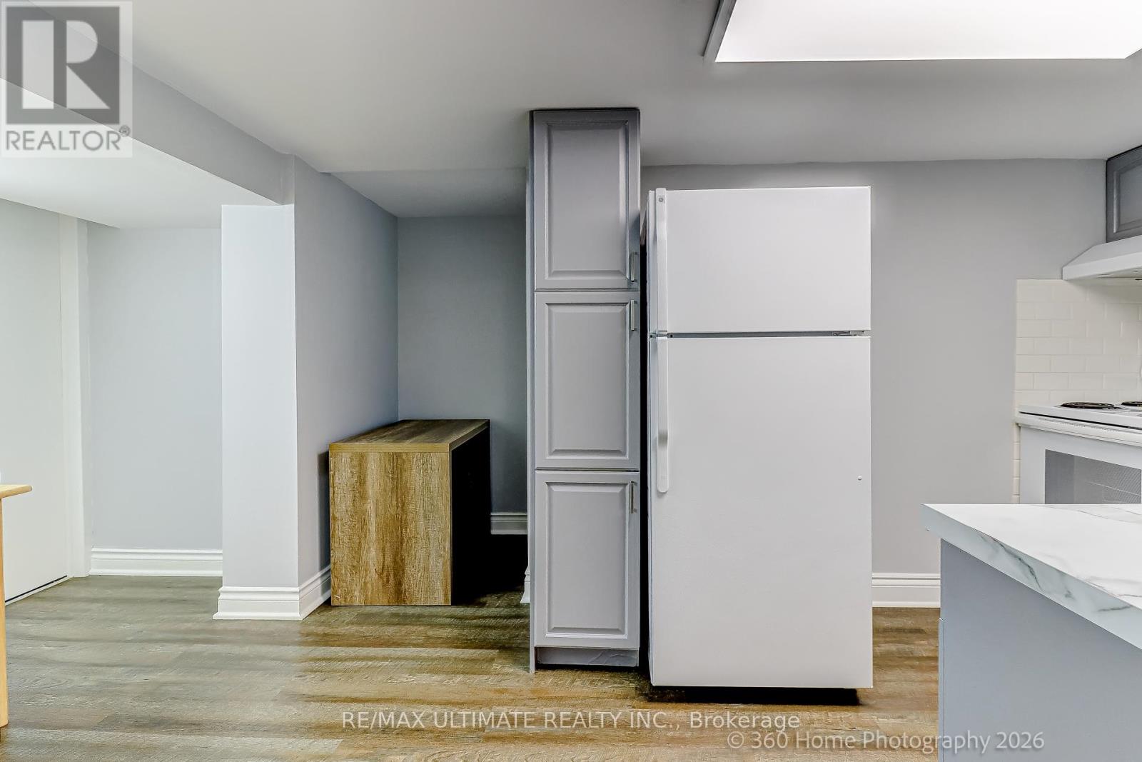 A white refrigerator is in a kitchen with a wooden box on the floor.