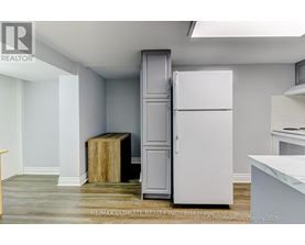 A white refrigerator is in a kitchen with a wooden box on the floor.