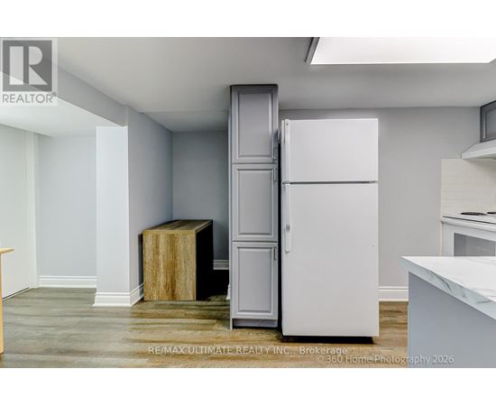 A white refrigerator is in a kitchen with a wooden box on the floor.