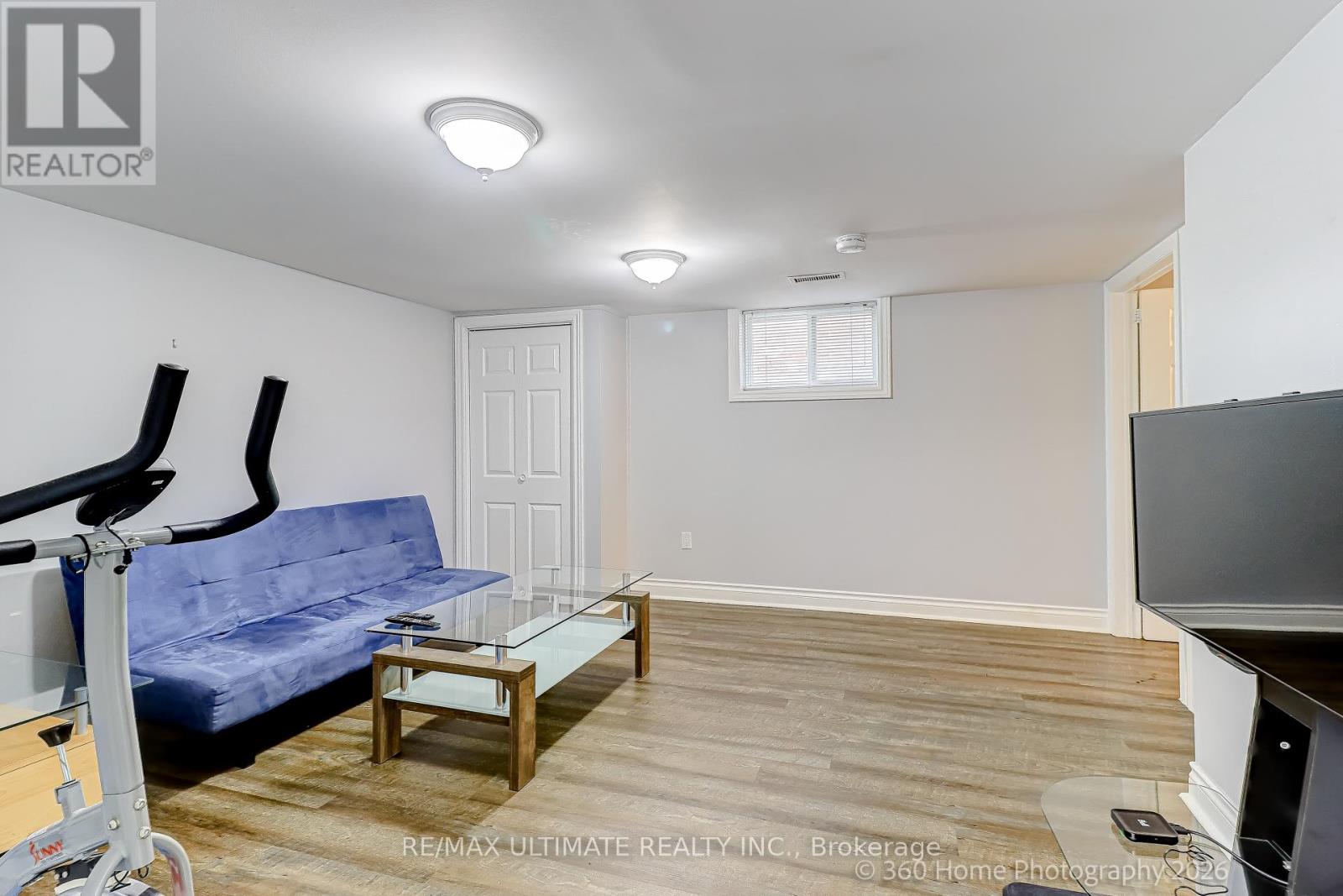A living room with a blue couch and a glass coffee table.