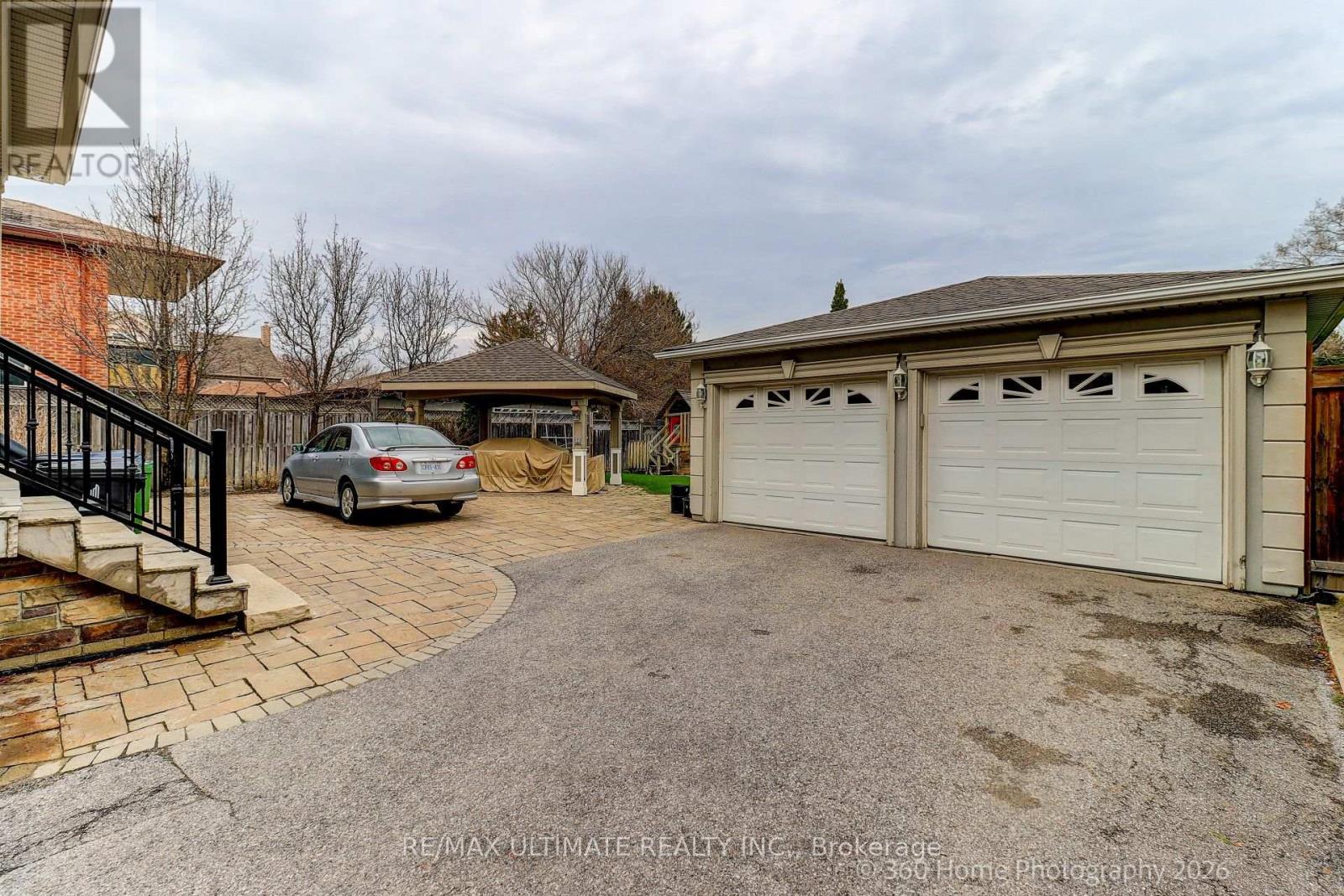 A car is parked in front of a house with a white garage door.