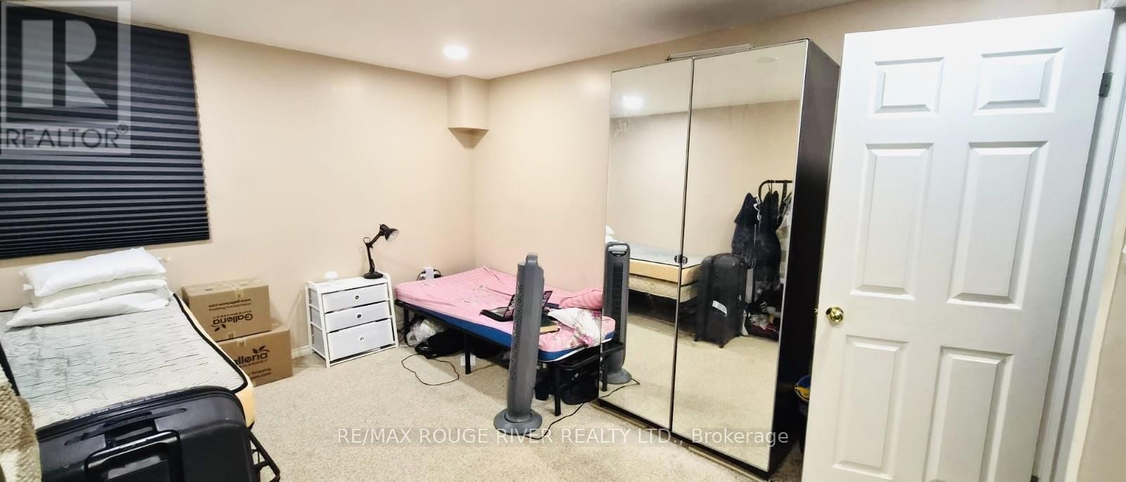 A bedroom with a bed, desk, and mirror.