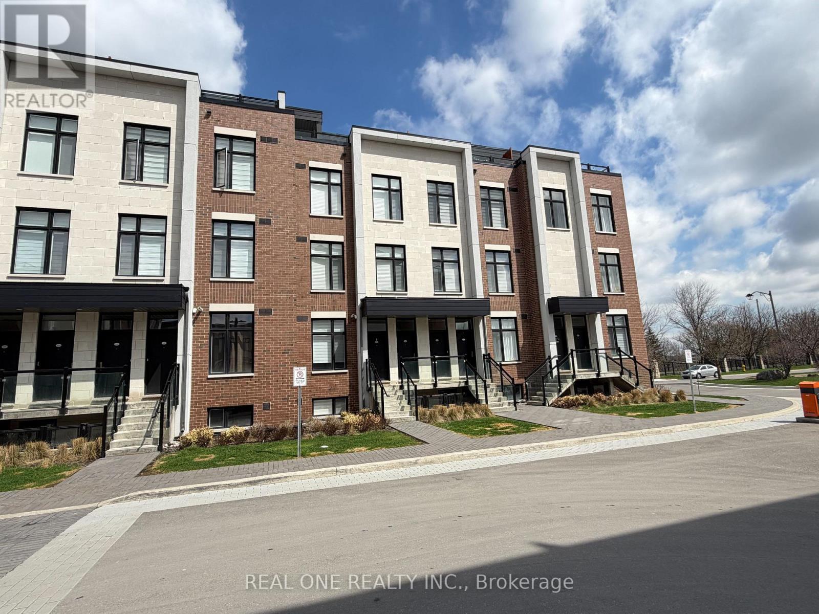A row of townhouses with the words REAL ONE REALTY INC. on the bottom.