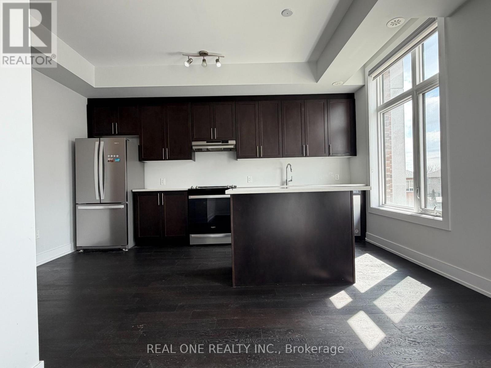 A kitchen with dark wood cabinets and a stainless steel refrigerator.
