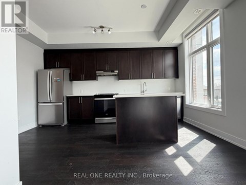 A kitchen with dark wood cabinets and a stainless steel refrigerator.
